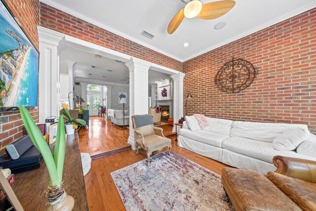 living room with crown molding, brick wall, and hardwood / wood-style flooring