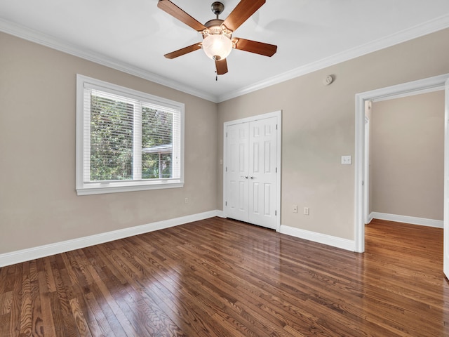 unfurnished bedroom with a closet, crown molding, ceiling fan, and dark wood-type flooring