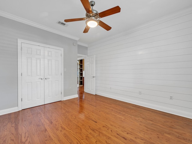 unfurnished bedroom with a closet, hardwood / wood-style flooring, ceiling fan, and ornamental molding