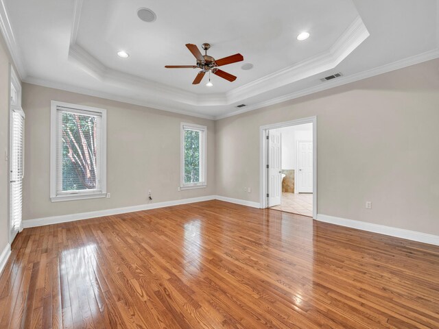 unfurnished room featuring light wood-type flooring, crown molding, a wealth of natural light, and a tray ceiling