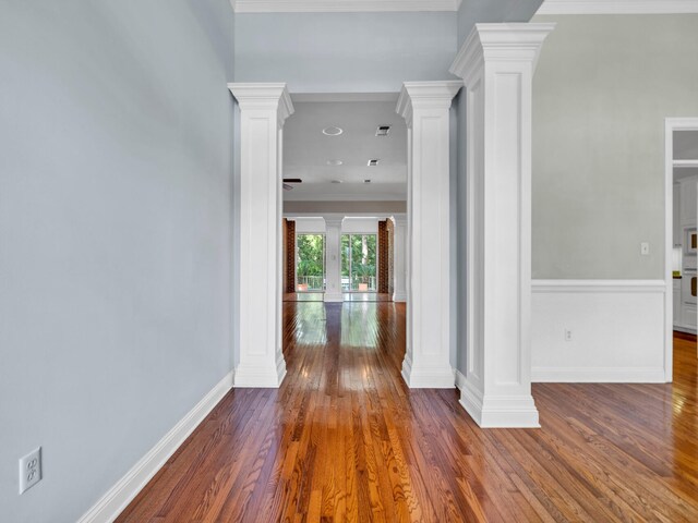 corridor featuring ornamental molding, dark wood-type flooring, and decorative columns