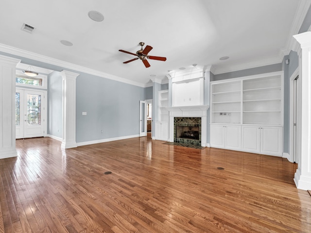 unfurnished living room with built in shelves, wood-type flooring, ceiling fan, and ornamental molding