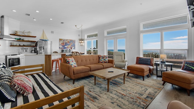 living room featuring light hardwood / wood-style flooring, a water view, and a notable chandelier