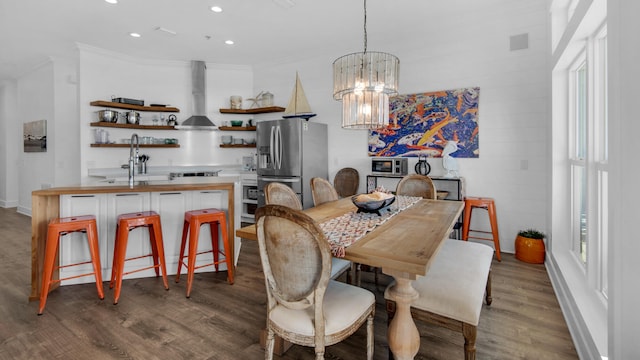 dining room with light wood-type flooring, an inviting chandelier, crown molding, and sink