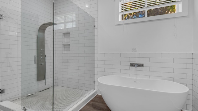 bathroom with wood-type flooring, tile walls, and plus walk in shower