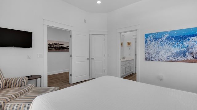 bedroom featuring ensuite bath and dark hardwood / wood-style floors