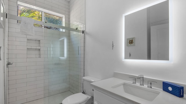 bathroom with vanity, toilet, and tiled shower