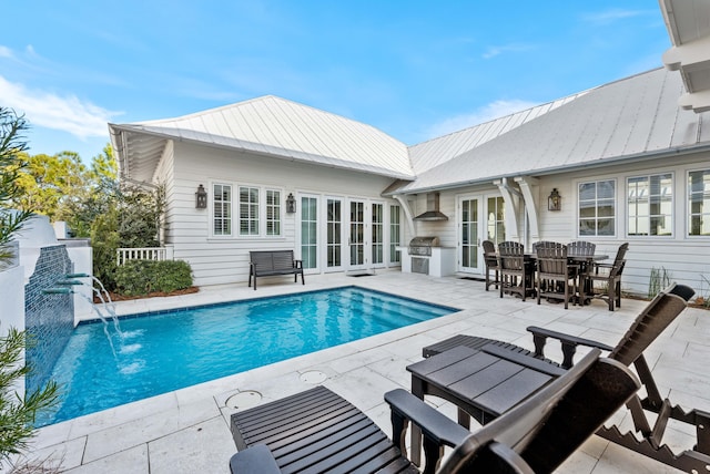 view of swimming pool featuring pool water feature, area for grilling, a patio area, and exterior kitchen