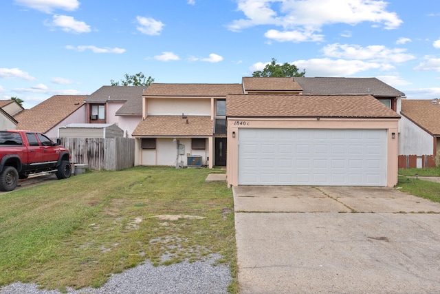 view of front of property with a garage, a front lawn, and central AC