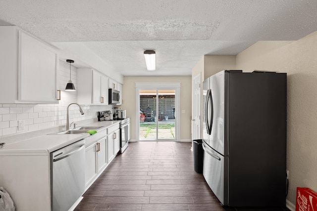 kitchen featuring a textured ceiling, decorative light fixtures, appliances with stainless steel finishes, dark wood-type flooring, and white cabinets