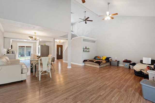 living room with ceiling fan with notable chandelier, high vaulted ceiling, and hardwood / wood-style flooring