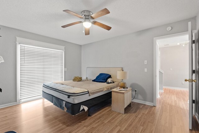 bedroom with a textured ceiling, ceiling fan, and light hardwood / wood-style floors