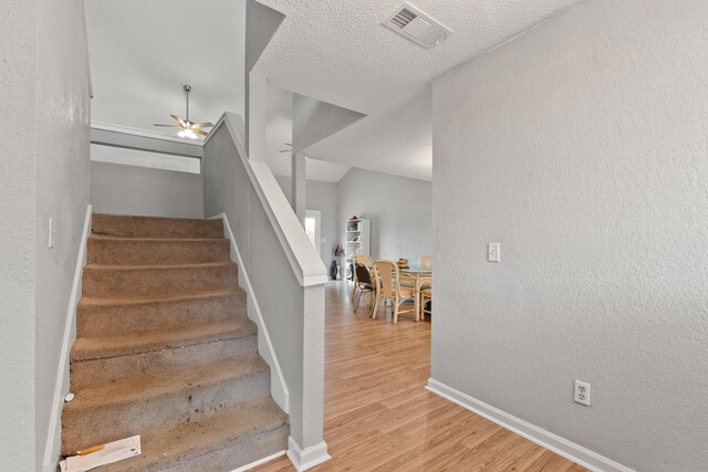 staircase featuring hardwood / wood-style flooring and ceiling fan