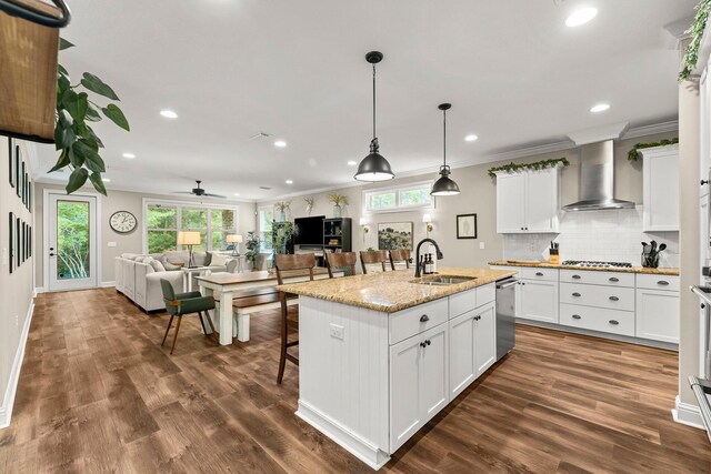 kitchen with a center island with sink, appliances with stainless steel finishes, dark wood-type flooring, sink, and light stone counters