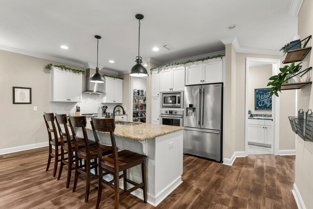 kitchen featuring sink, wall chimney range hood, appliances with stainless steel finishes, and white cabinetry