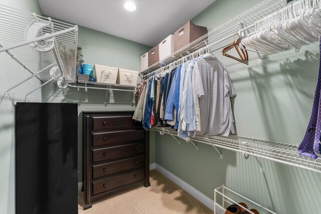 walk in closet with light colored carpet