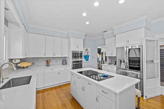 kitchen with light wood-type flooring, sink, white cabinetry, stainless steel appliances, and light stone countertops