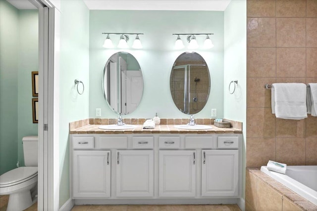 bathroom with tiled bath, vanity, and toilet