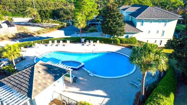 view of pool featuring a patio, a pool with connected hot tub, and fence