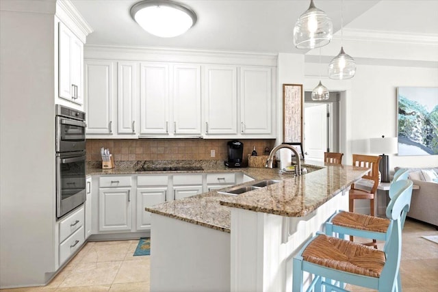 kitchen featuring a kitchen breakfast bar, tasteful backsplash, white cabinets, and pendant lighting