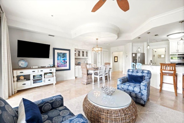 living room featuring ceiling fan with notable chandelier, a tray ceiling, crown molding, and sink