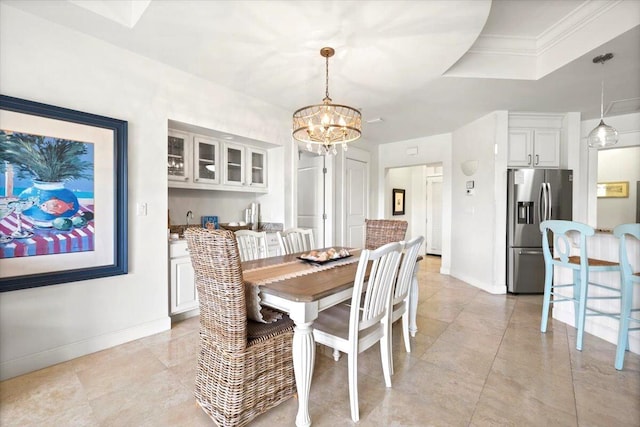 dining space with a raised ceiling, crown molding, and a notable chandelier