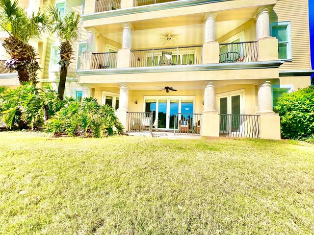 rear view of property with ceiling fan, a yard, and a balcony