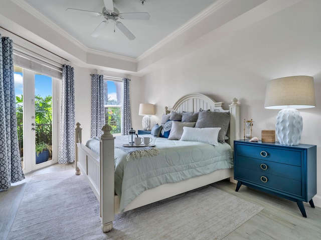 bedroom with crown molding, ceiling fan, wood finished floors, a raised ceiling, and access to outside