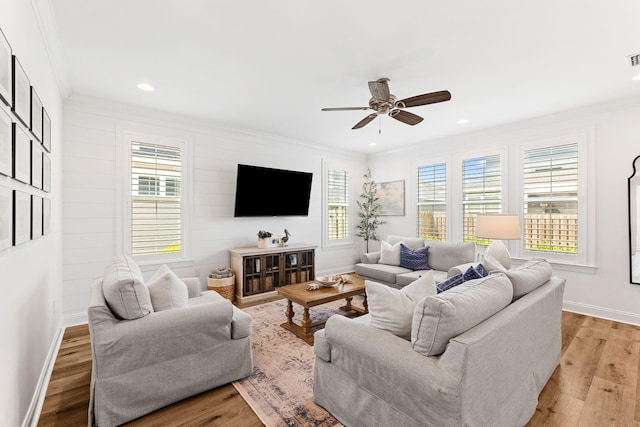 living room with light wood-type flooring, crown molding, a healthy amount of sunlight, and ceiling fan