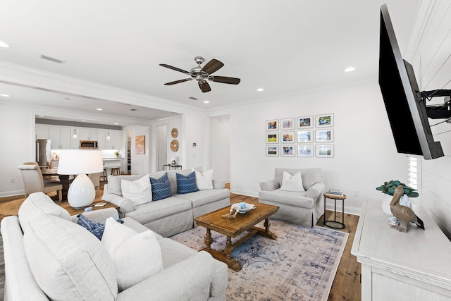 living room with crown molding, wood-type flooring, and ceiling fan