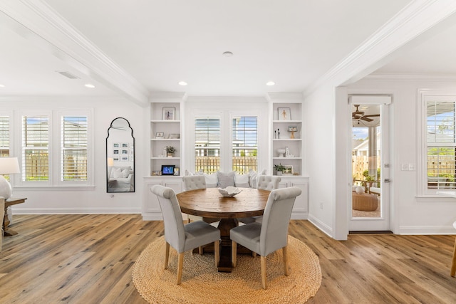 dining space with light wood-type flooring, built in features, plenty of natural light, and ornamental molding