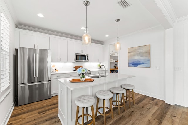 kitchen featuring appliances with stainless steel finishes, dark hardwood / wood-style flooring, a center island with sink, and white cabinets