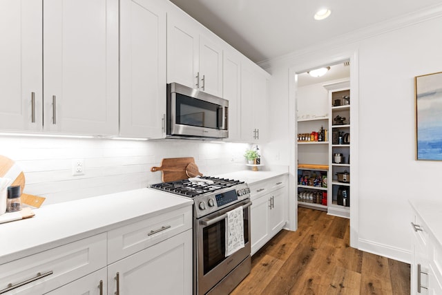 kitchen with white cabinetry, backsplash, appliances with stainless steel finishes, and dark hardwood / wood-style flooring