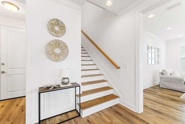 stairway featuring crown molding and hardwood / wood-style flooring