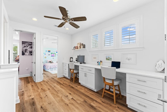 office with built in desk, a wealth of natural light, ceiling fan, and light hardwood / wood-style floors