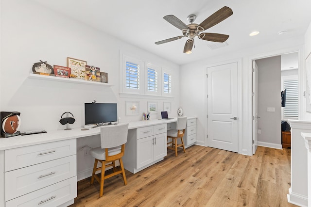 office area with built in desk, ceiling fan, and light hardwood / wood-style floors