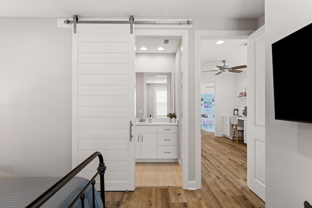 hall featuring a barn door, sink, and light hardwood / wood-style flooring