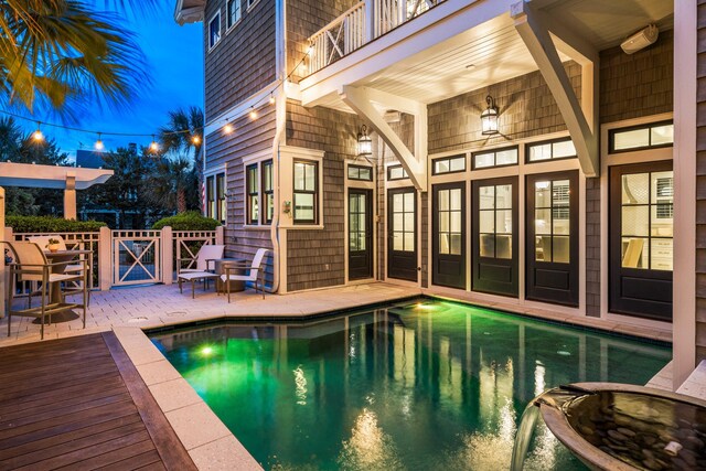 pool at night featuring a patio area