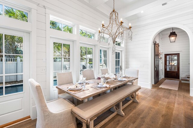 dining area featuring hardwood / wood-style floors, an inviting chandelier, and beam ceiling