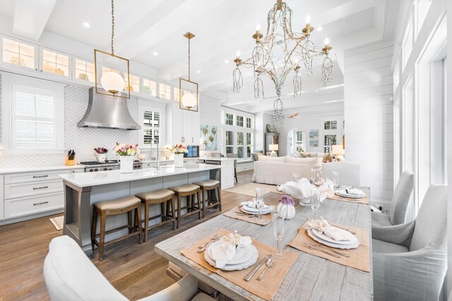 dining area with beamed ceiling, hardwood / wood-style flooring, and a chandelier