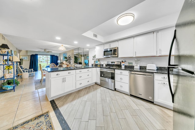 kitchen featuring kitchen peninsula, stainless steel appliances, and white cabinets