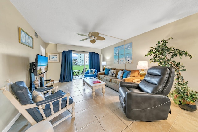 living room featuring a textured ceiling, ceiling fan, and light tile patterned flooring