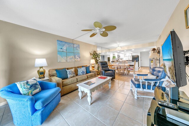 living room with ceiling fan, light tile patterned floors, and a textured ceiling