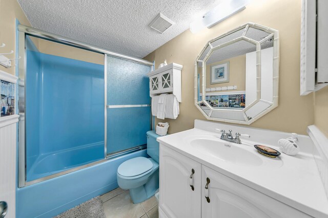 full bathroom featuring tile patterned floors, toilet, shower / bath combination with glass door, vanity, and a textured ceiling