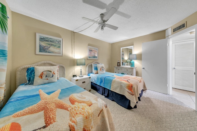 carpeted bedroom with a textured ceiling, ceiling fan, and a closet