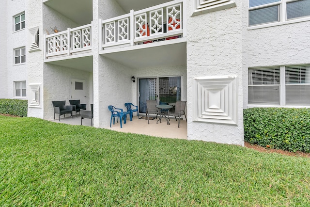 exterior space with a balcony, a yard, and a patio