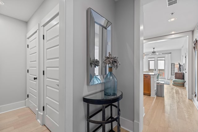 hallway with recessed lighting, visible vents, baseboards, and light wood finished floors