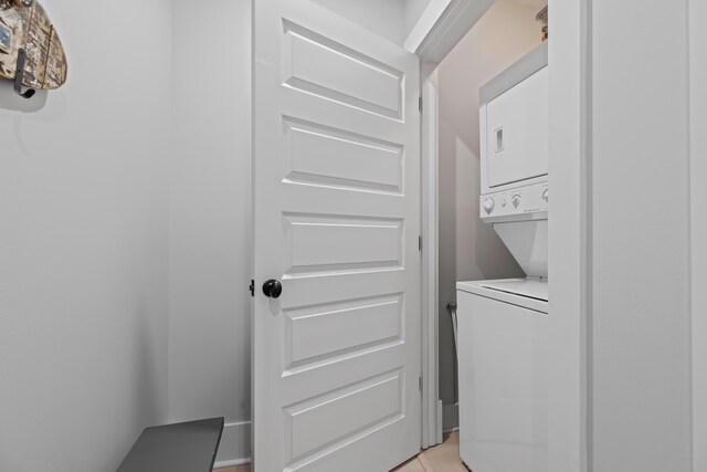 laundry area featuring light tile patterned floors and stacked washing maching and dryer