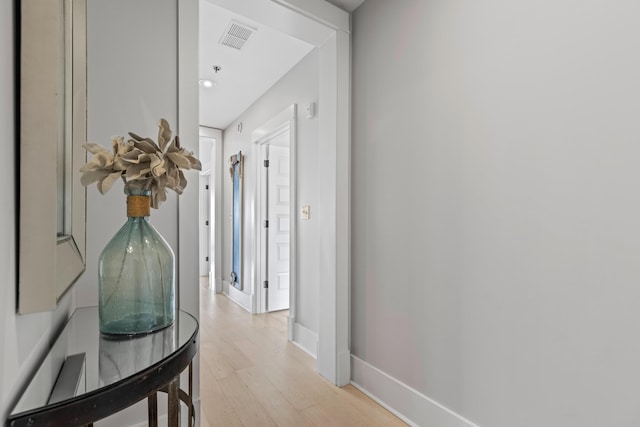 corridor with visible vents, light wood-style flooring, and baseboards