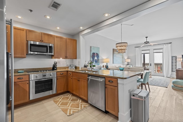 kitchen with visible vents, open floor plan, appliances with stainless steel finishes, a peninsula, and a sink